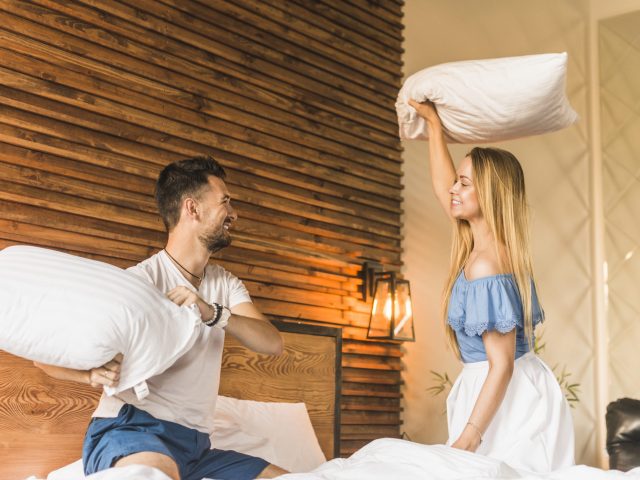lovely-young-couple-having-pillow-fight-bed